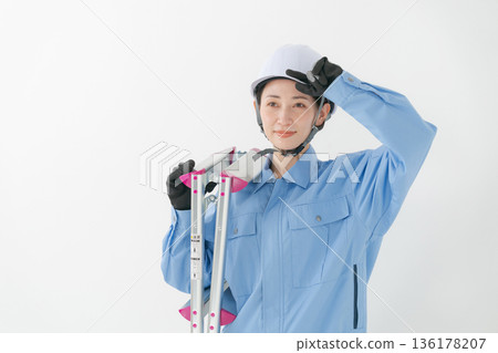A woman in work clothes wearing a helmet A woman in work clothes wearing a helmet 136178207