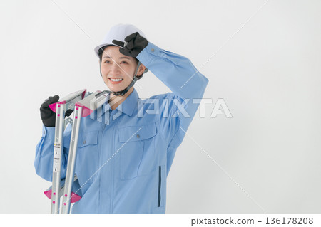 A woman in work clothes wearing a helmet A woman in work clothes wearing a helmet 136178208