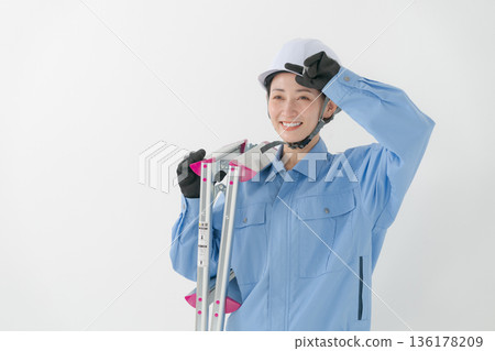 A woman in work clothes wearing a helmet A woman in work clothes wearing a helmet 136178209