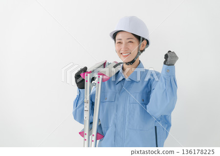 A woman in work clothes wearing a helmet A woman in work clothes wearing a helmet 136178225