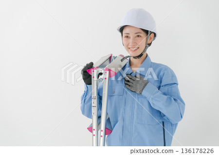 A woman in work clothes wearing a helmet 136178226