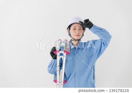 A woman in work clothes wearing a helmet A woman in work clothes wearing a helmet 136178228