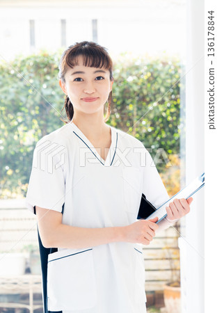 A female medical worker wearing a scrub and standing by the window A female medical worker wearing a scrub and standing by the window 136178844