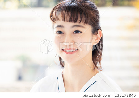 A female medical worker wearing a scrub and standing by the window A female medical worker wearing a scrub and standing by the window 136178849