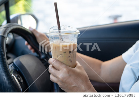 Asian lady driver holding ice coffee in car. Asian lady driver holding ice coffee in car. 136179095
