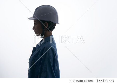 A woman in work clothes wearing a helmet A woman in work clothes wearing a helmet 136179225