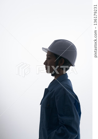 A woman in work clothes wearing a helmet A woman in work clothes wearing a helmet 136179231