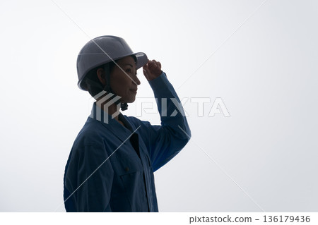 A woman in work clothes wearing a helmet A woman in work clothes wearing a helmet 136179436