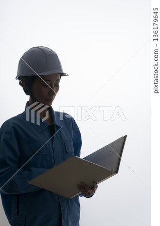 A woman in work clothes wearing a helmet A woman in work clothes wearing a helmet 136179645