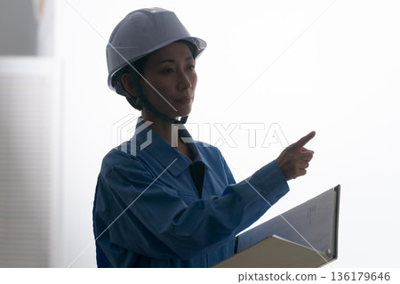 A woman in work clothes wearing a helmet A woman in work clothes wearing a helmet 136179646