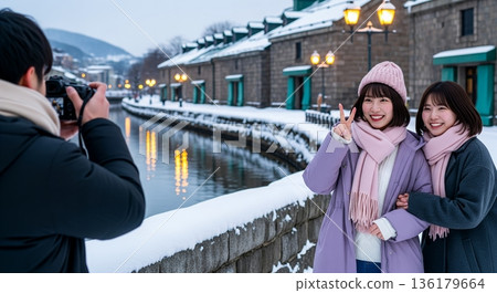 在旅遊景點，一名男子正在為兩名女子拍照。 136179664