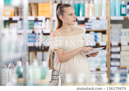 Pregnant woman looking for medicaments according to prescription Pregnant woman looking for medicaments according to prescription 136179979