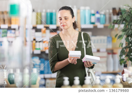 woman chooses packages of pills in a pharmacy woman chooses packages of pills in a pharmacy 136179980