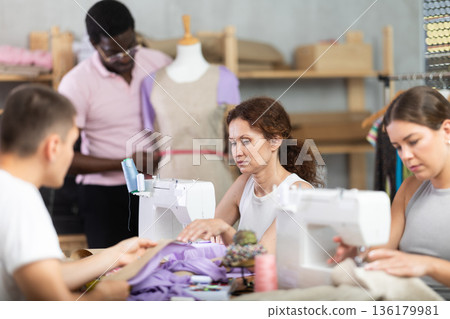 Positive woman working at machine during group sewing course for adults 136179981