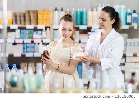 Pregnant woman choosing syrup with help of pharmacist Pregnant woman choosing syrup with help of pharmacist 136180003