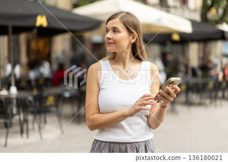 Female pedestrian with phone in summer European capital Female pedestrian with phone in summer European capital 136180021