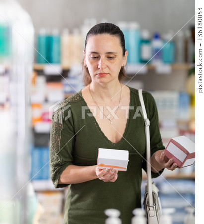 woman chooses packages of pills in a pharmacy 136180053