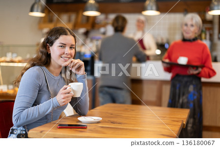 Girl whiles away time and waits for meeting in chain cafe 136180067