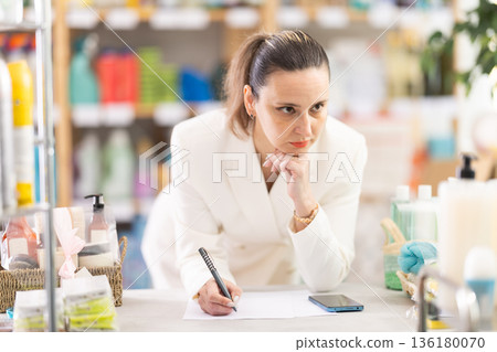 Adult woman conducting inventory with checklist and phone 136180070