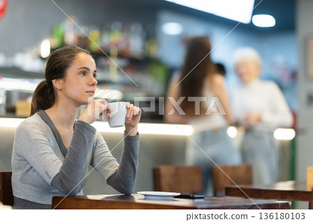 Girl whiles away time and drink coffee in cafe 136180103