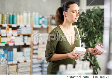 woman chooses packages of pills in a pharmacy woman chooses packages of pills in a pharmacy 136180175