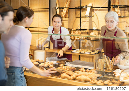 Helpful bakery salesmen selling bread and buns to customers Helpful bakery salesmen selling bread and buns to customers 136180207