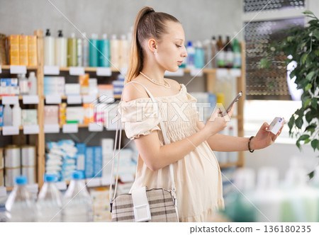 Pregnant woman customer scanning QR-code on paracetamol box Pregnant woman customer scanning QR-code on paracetamol box 136180235
