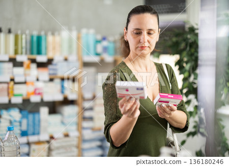 Middle-aged woman customer choosing paracetamol in drugstore 136180246
