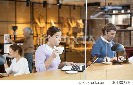 Woman spending time in cozy coffeehouse with laptop and coffee 136180259