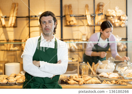 Baker wearing apron while working behind counter in small bakery 136180266
