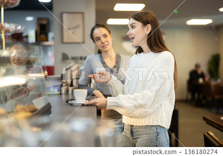 Two women talking and drinking coffee in cafe 136180274