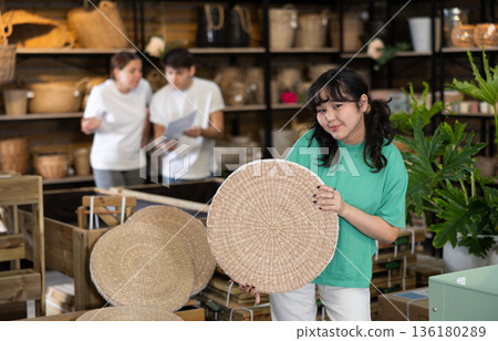 Young asian girl choosing wicker seat at home decor store Young asian girl choosing wicker seat at home decor store 136180289