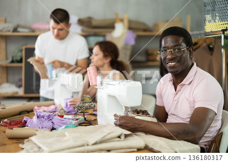 Students work with sewing machines under guidance of teacher 136180317