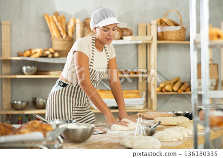 Young woman works in bakery as baker, kneads and prepare dough, works with flour. Young woman works in bakery as baker, kneads and prepare dough, works with flour. 136180335