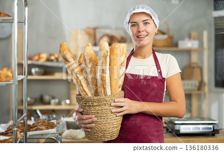 Young woman are standing in kitchen with basket of finished products baguettes Young woman are standing in kitchen with basket of finished products baguettes 136180336