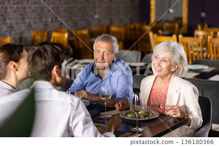 Elderly couple and young couple having dinner in restaurant Elderly couple and young couple having dinner in restaurant 136180366