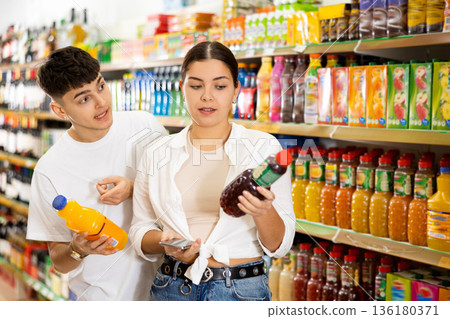 Positive young couple choosing drinks in grocery store Positive young couple choosing drinks in grocery store 136180371