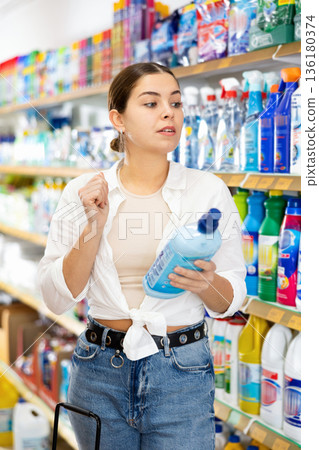 Girl looking for household detergents on shelves in store Girl looking for household detergents on shelves in store 136180374