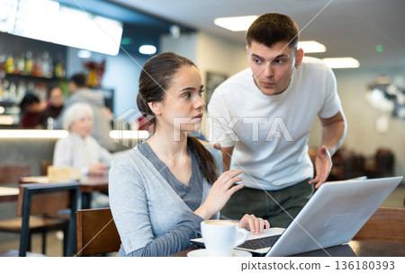 Girl asks her boyfriend not to disturb her while he works on his laptop in cafe 136180393
