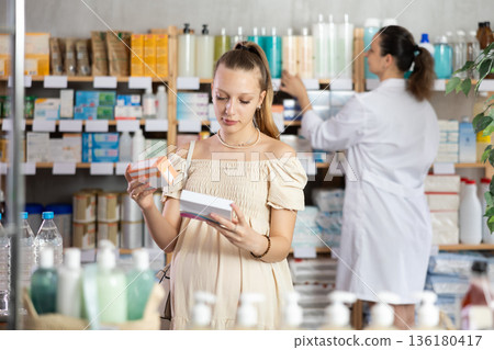 Pregnant woman chooses pills at pharmacy Pregnant woman chooses pills at pharmacy 136180417