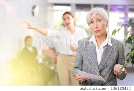 Upset aged female office worker scolded by angry woman boss Upset aged female office worker scolded by angry woman boss 136180423