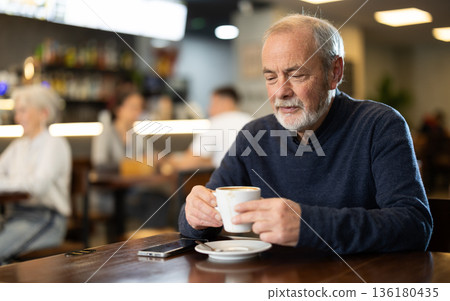 Elderly man drinks coffee in cafe interior 136180435
