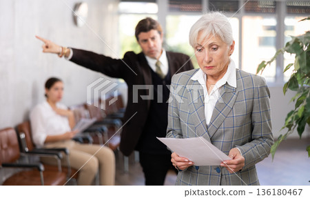 Businessman yelling at mature woman manager in office 136180467