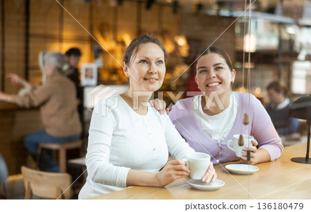 Carefree female colleagues drinking coffee and chatting in cafe 136180479