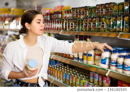in shop, woman chooses mayonnaise. 136180505