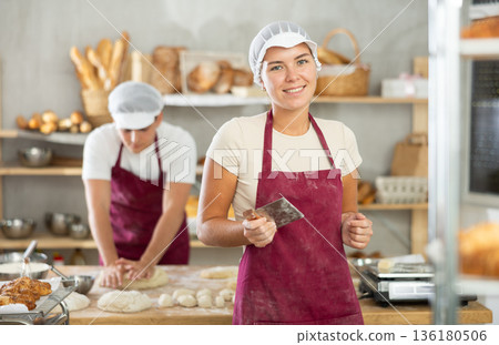 Young female baker holding a dough cutter in bakery 136180506