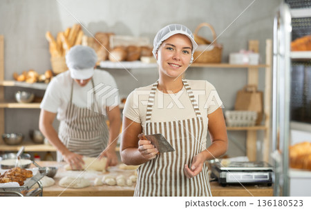 Young female baker holding a dough cutter in bakery 136180523