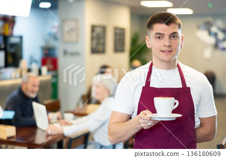 Barista guy with a cup of cappuccino in a cafe 136180609