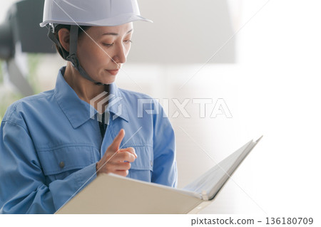 一位身穿工作服的女士正在查看藍圖 136180709