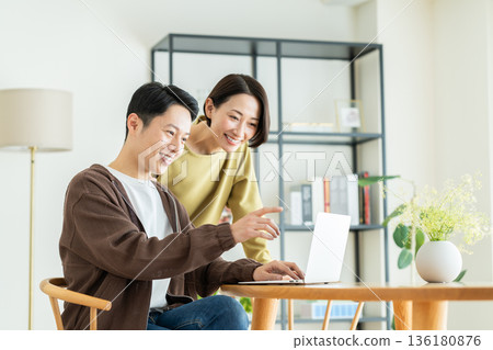 Middle-aged couple looking at a computer at home Middle-aged couple looking at a computer at home 136180876